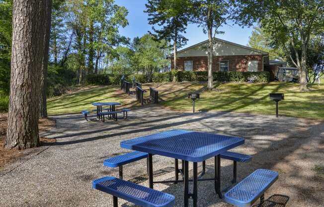 a picnic area with tables and benches and a building in the background