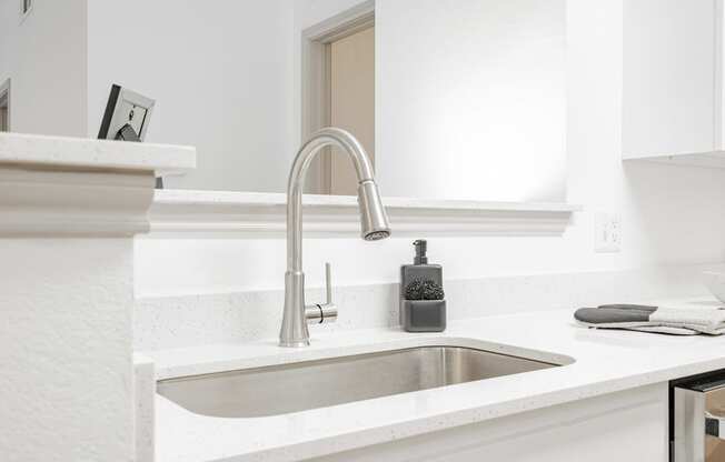 a white kitchen with a sink and a faucet