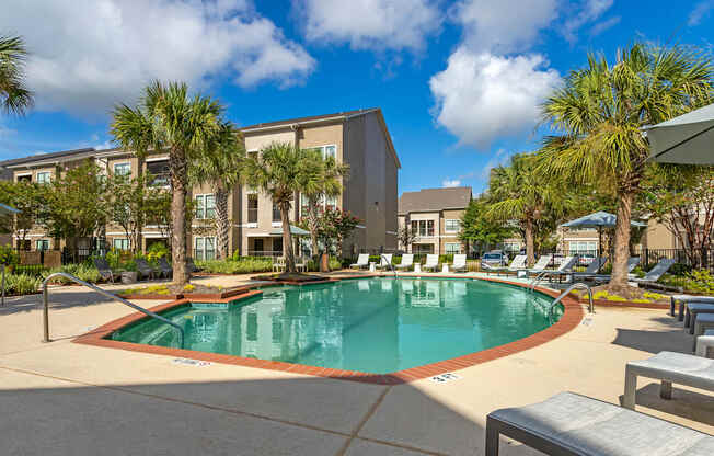 a swimming pool with palm trees and a building in the background at Summerwind, Texas, 77584
