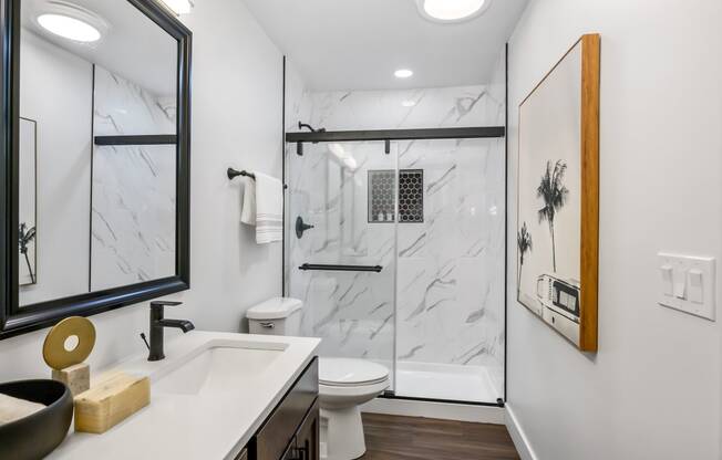 a bathroom with a toilet sink and shower with a glass door