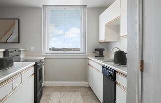 A kitchen with white cabinets and a black dishwasher.