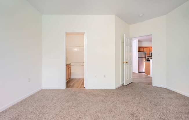 a living room with carpet and a door to a kitchen