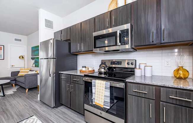A modern kitchen with a stainless steel refrigerator, microwave, and oven.