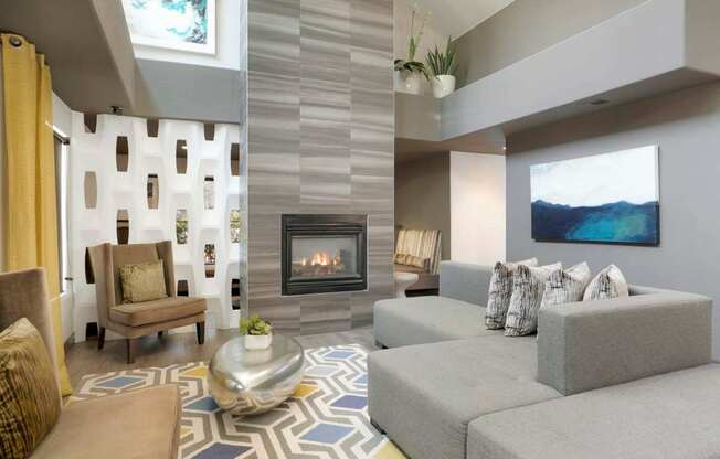 A modern living room with a fireplace and grey couches.