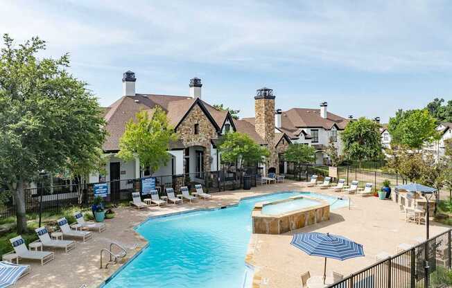 Aerial view of resort-style pool with sundeck and stone clubhouse at Villas of Vista Ridge.