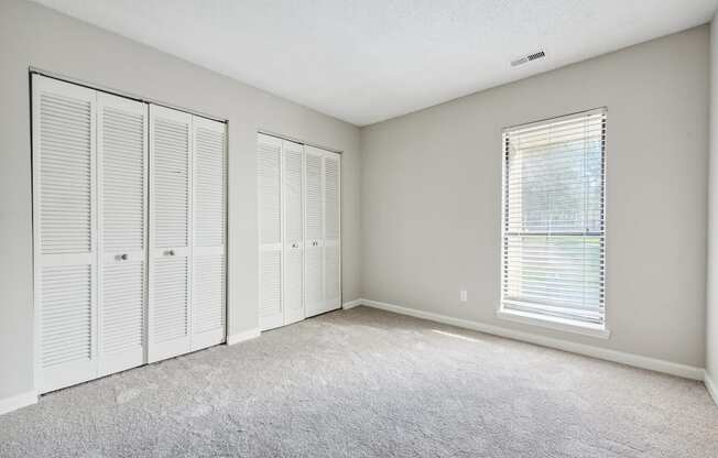 A room with white closets and a carpeted floor.