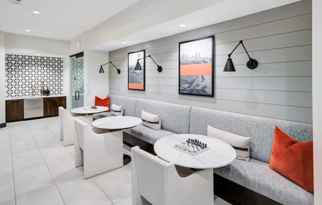 a seating area with white tables and chairs and a gray couch