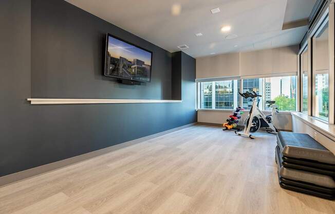 A room with a television on the wall and a row of exercise equipment.
