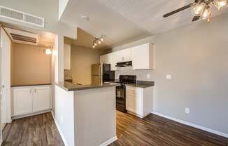 A kitchen with white cabinets and a wooden floor.