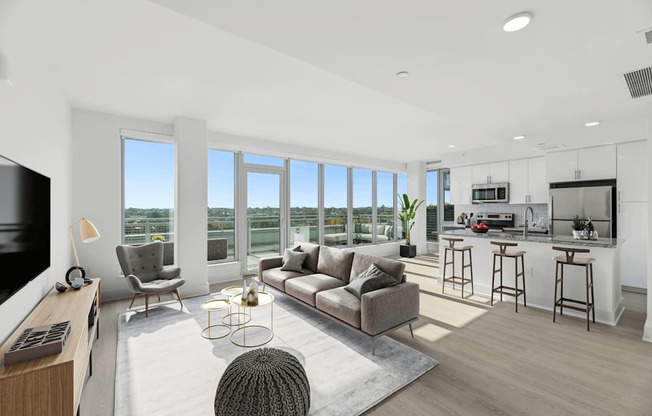 an open living room with a couch and a chair and a kitchen with a counter