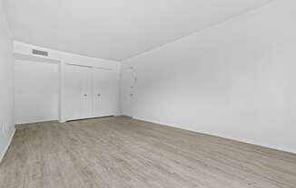 a bedroom with hardwood floors and white walls