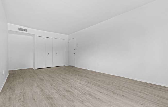 a bedroom with hardwood floors and white walls