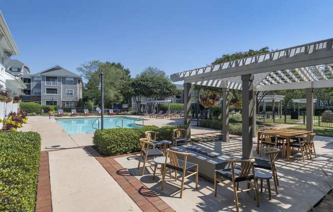 Outdoor lounge next to a pool at Seasons at Umstead apartments in Raleigh