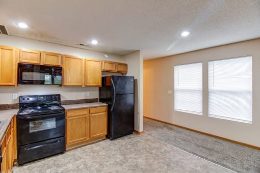 an empty kitchen with black appliances and wooden cabinets