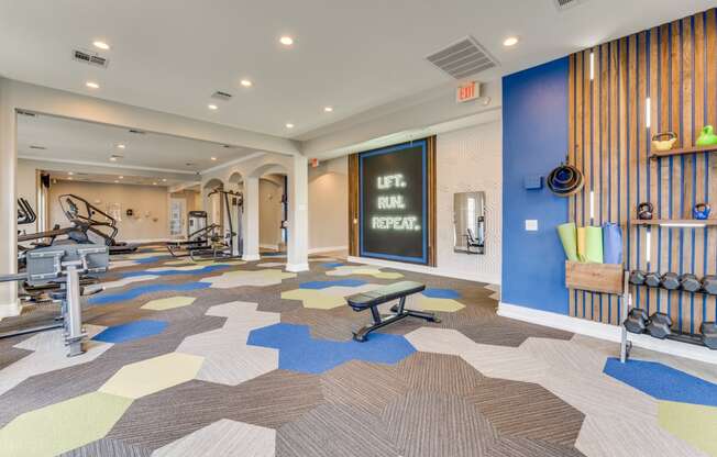a gym with weights and cardio machines and a chalkboard on the wall