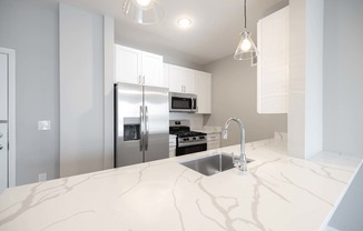 A kitchen with a marble countertop and stainless steel appliances.