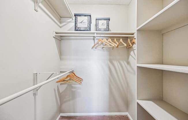 A white closet with a hanger and two clocks on the shelf.