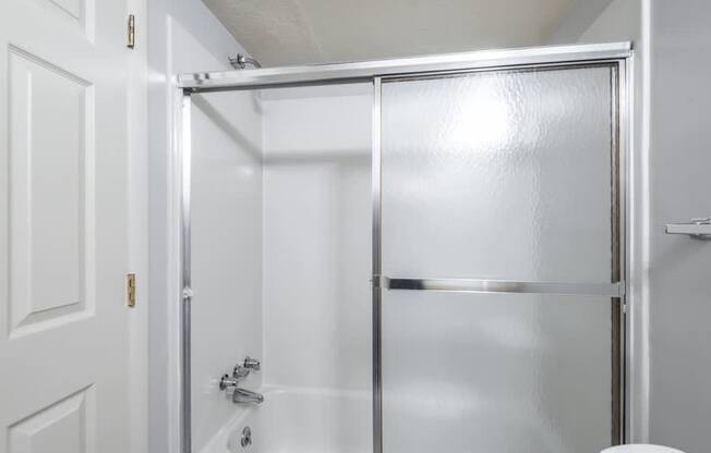 A white door with a silver handle and a white toilet in a bathroom.