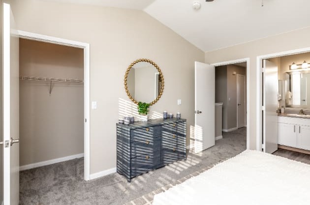A bathroom with a round mirror and a plant on a cabinet.