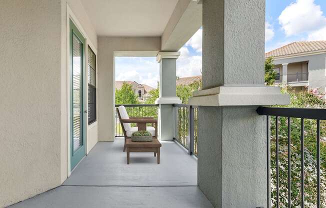 A balcony with a chair and a table with a plant on it.
