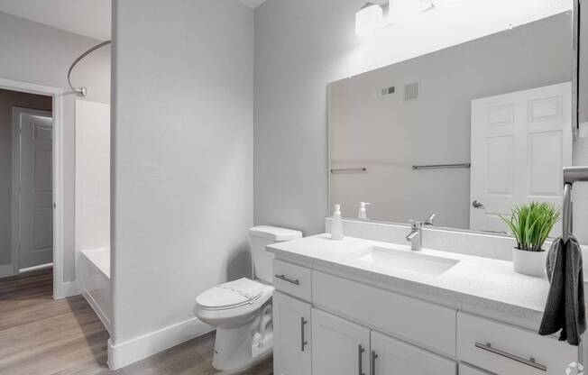 A white bathroom with a toilet, sink, and mirror.