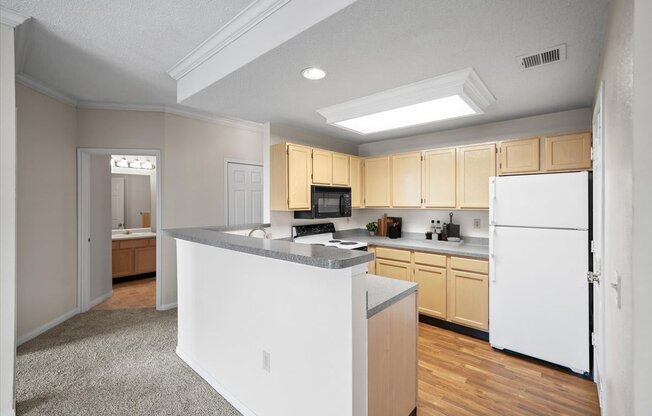A kitchen with white appliances and wooden cabinets.