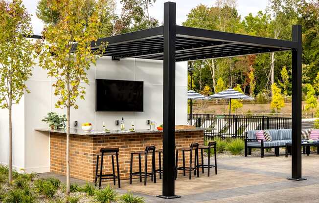 A small outdoor bar with a black canopy and a television mounted above it.