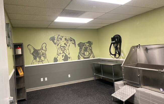 A room with a mural of dogs on the wall and a stainless steel sink.