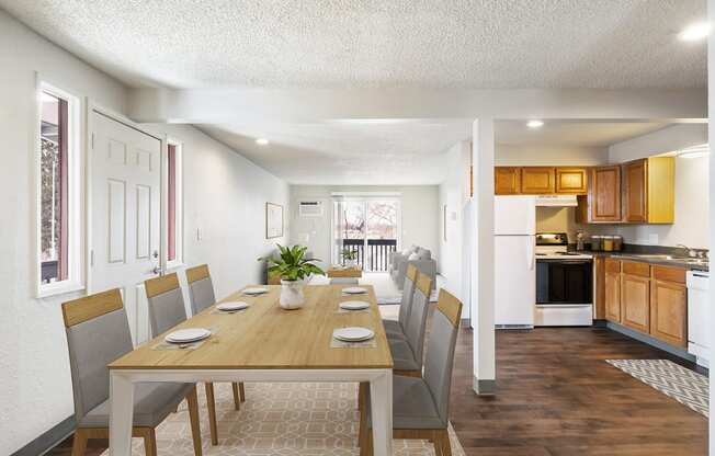 A dining area with a wooden table and chairs and a kitchen and living room in the background.at Wildflower, Kennewick, WA 99336
