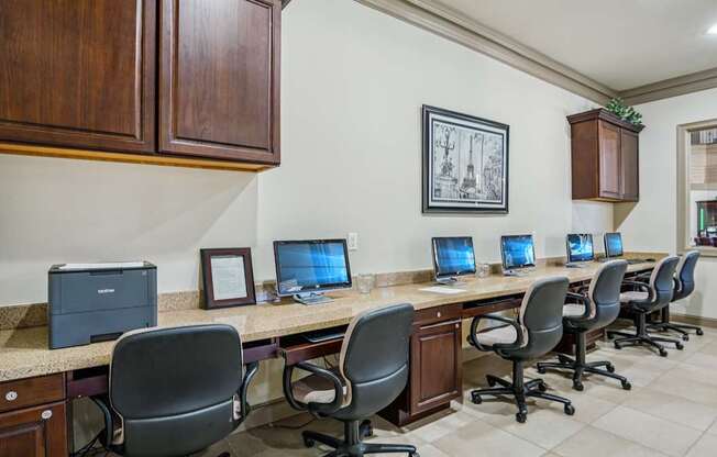 A row of computers are on a desk in a room with wood paneling.