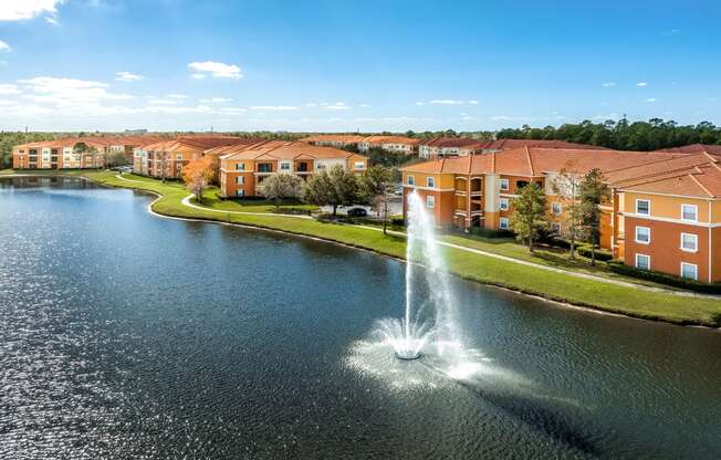 a fountain in the middle of a lake with an apartment complex in the background