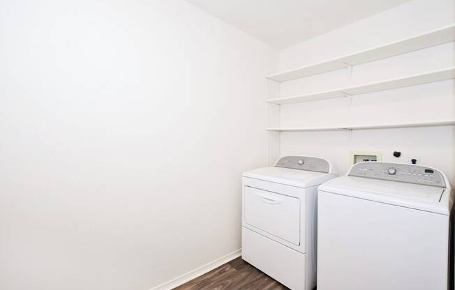 a white washer and dryer in a room with white walls and wood floors