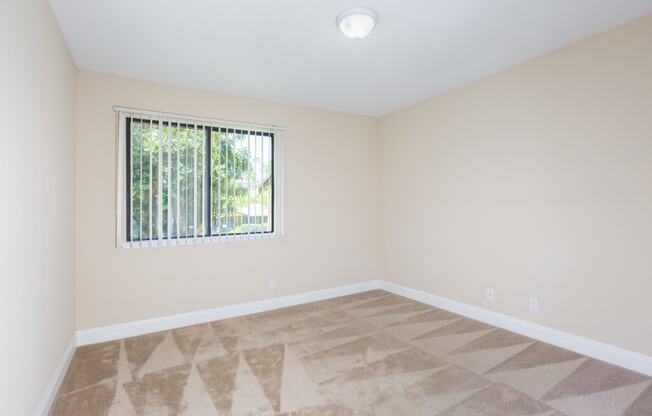 an empty living room with a window and tiled floors
