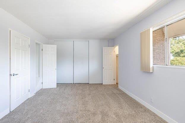 A room with white walls and a carpeted floor with a window on the right side.
