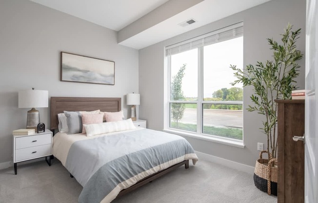 A bedroom with a large bed, two lamps, and a painting on the wall.