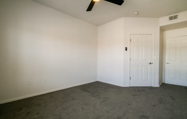 a bedroom with white walls and a ceiling fan