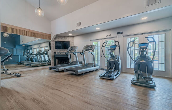 a gym with cardio machines and a fireplace