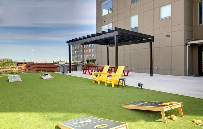 A modern building with a patio area featuring a bean bag, chairs and a table.