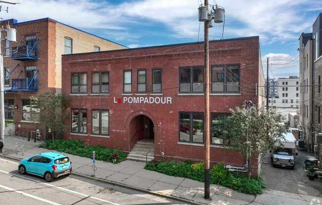 a red brick building with a blue car parked in front of it
