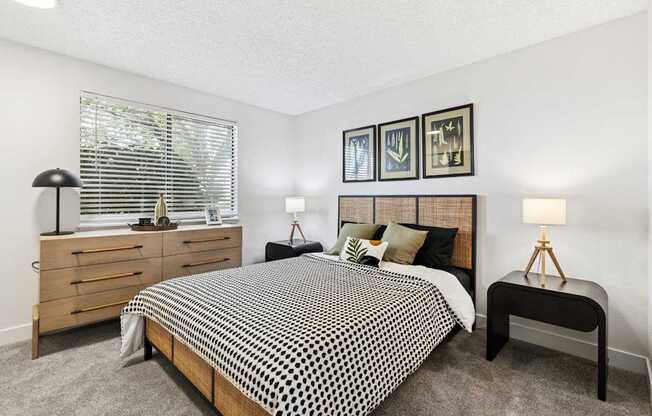 A bedroom with a bed, nightstands, and pictures on the wall.