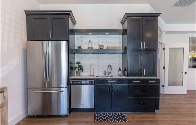A kitchen with a stainless steel refrigerator and black cabinets at Forestplace Apartment Homes, Forest Grove