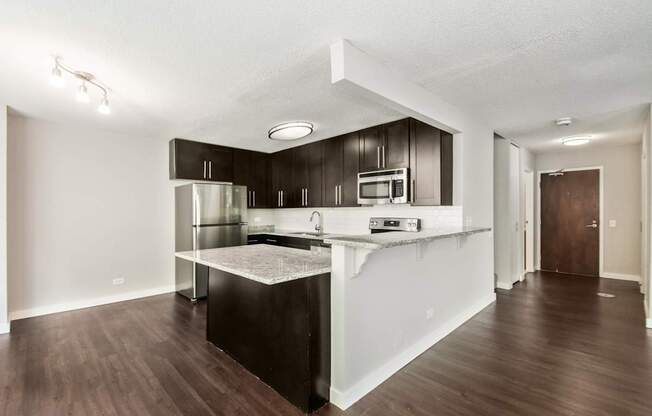 A kitchen with dark wood floors and white walls.