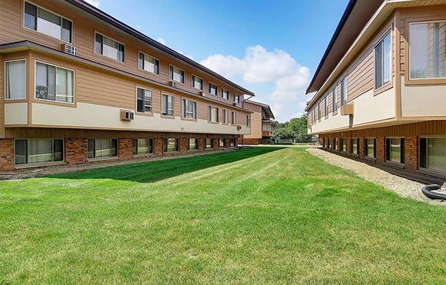 a row of apartment buildings with a grass yard