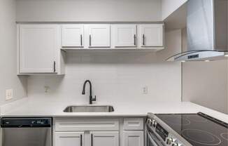 White kitchen counter with undermount sink, white tile backsplash, and electric range.