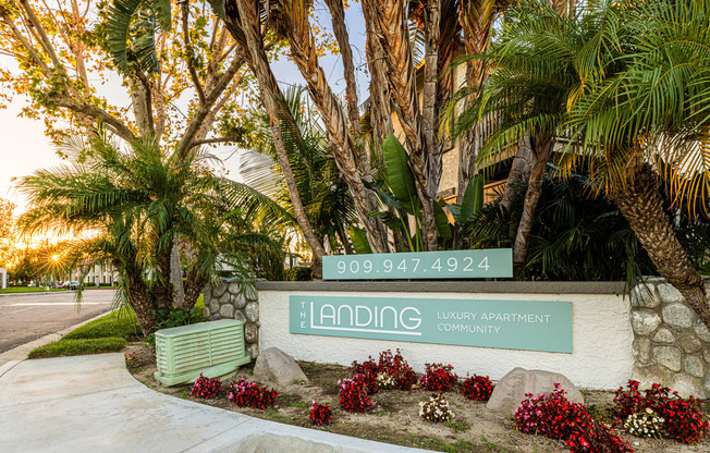 a green and white sign with palm trees and a bench