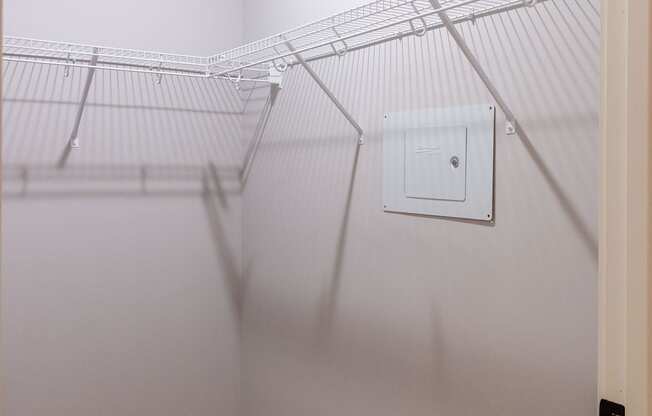 A white wall with a white door and a white electrical outlet.