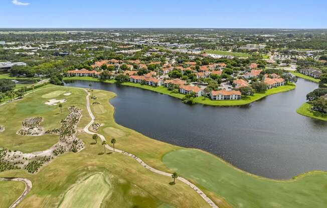 A golf course with a lake and houses in the background.