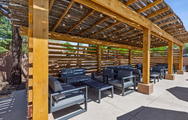 a covered patio with chairs and tables under a wooden structure at Acacia Gardens, Albuquerque, NM