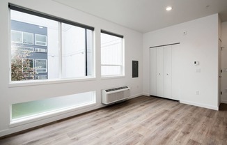 a living room with white walls and wood floors and a radiator and three windows