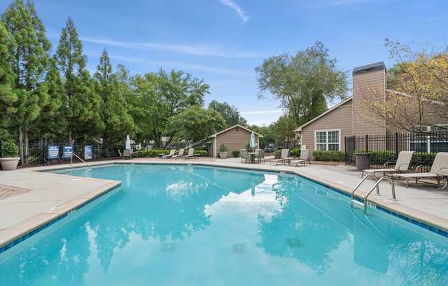 A large swimming pool surrounded by trees and chairs.